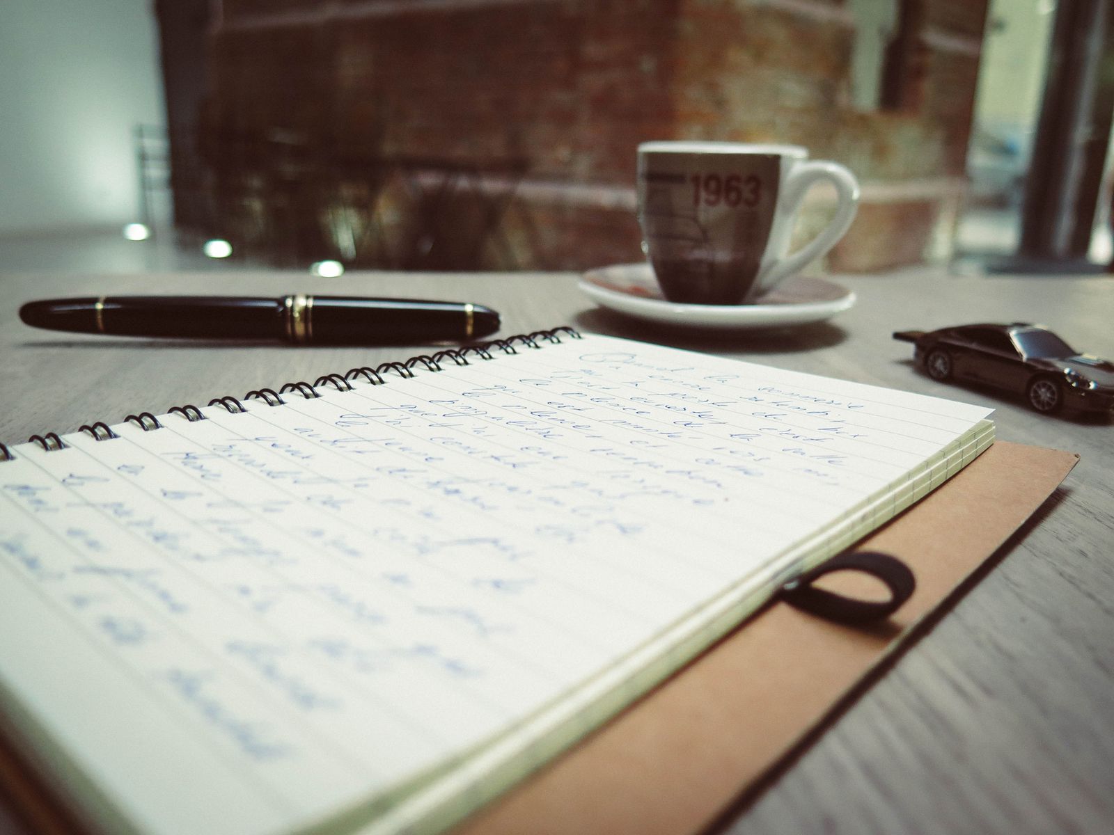 Un cuaderno de notas junto a un café sobre un escritorio.